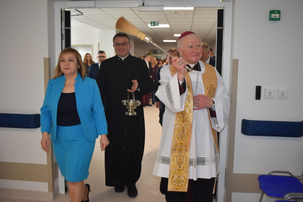 biskup święci oddział rehabilitacji, za nim dyrektorka szpitala i kapelan