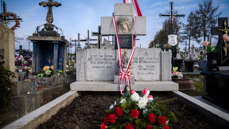 grób rodziny Ulmów w Markowej, położone są na nim biało-czerwone kwiaty, krzyż opasany jest biało-czerwoną wstęgą