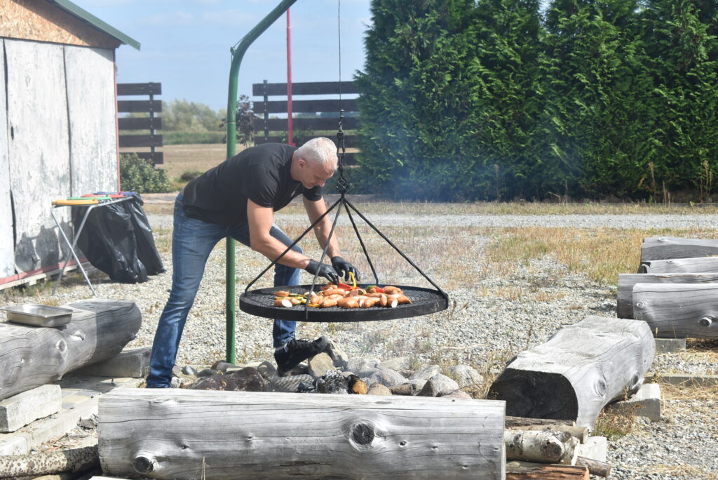 mężczyzna przy palenisku zajmuje się grillowanymi potrawami