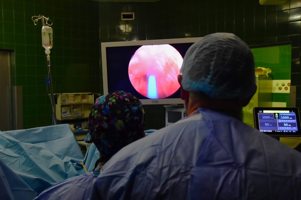 sala operacyjna, trwa zabieg, dwaj lekarze prowadzą zabieg laparoskopowy, patrzą w monitor, który pokazuje obraz z kamery laparoskopu