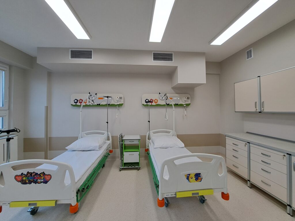 sala szpitalna, dwa łóżka, jasne ściany, kolorowe meble i motywy na ścianach