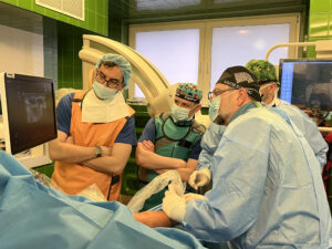 czterech lekarzy przy pacjencie, wpatrują się w monitor na którym obserwują obraz USG