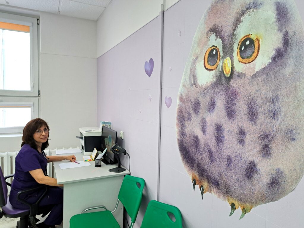 gabinet poradni neonatologicznej, lekarka siedzi przy biurku z komputerem, na ścianie namalowana ogromna sowa
