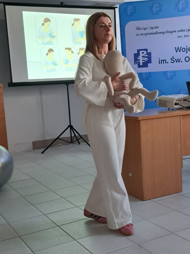 fizjoterapeutka na lalce demonstruje jak nosić niemowlaka