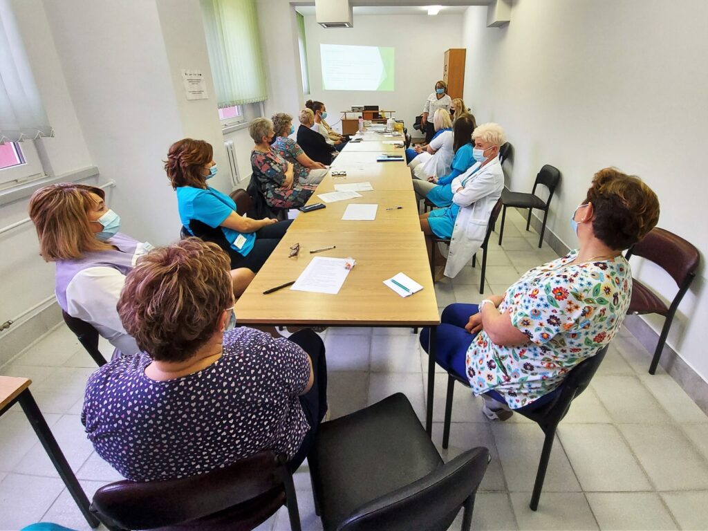 przy długim stole siedzą uczestnicy szkolenia, na końcu prowadząca