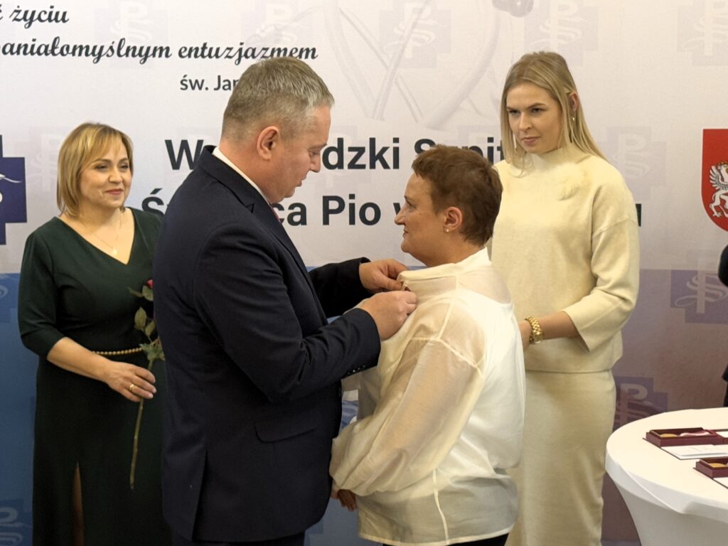 wicewojewoda przypina medal odznaczonej kobiecie, w tle dyrektorka spzitala i kobieta asystująca w dekoracji