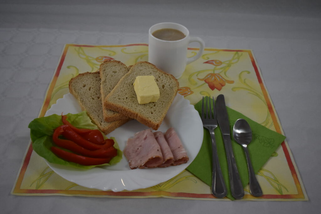 chleb w kromkach, masło, wędlina i papryka w plastrach, kawa z mlekiem