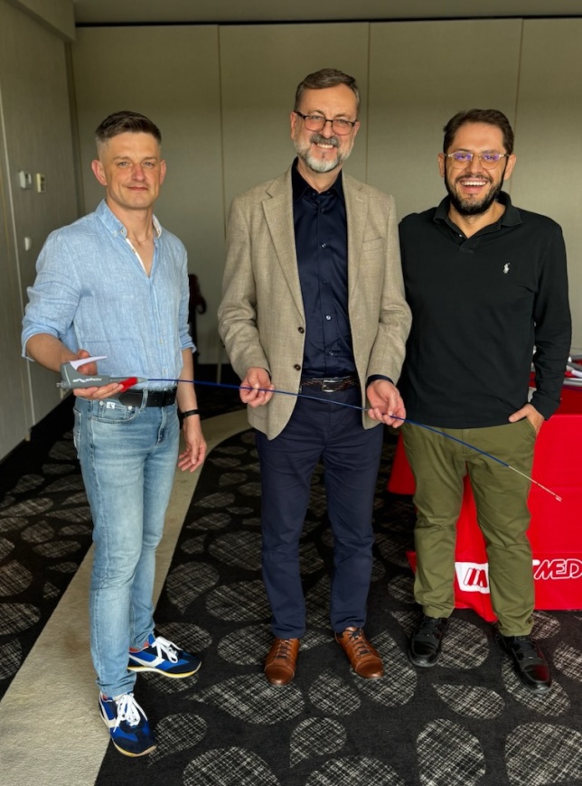 Trzech mężczyzn stoi obok siebie, trzymają stent żylny