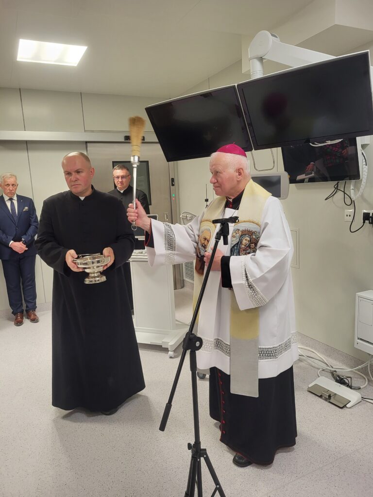 biskup święci salę operacyjną, obok kapelan szpitala