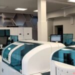 pracownia laboratoryjna, nowoczesne maszyny diagnostyczne w kolorze białym, w tle monitory komputerów, szafki