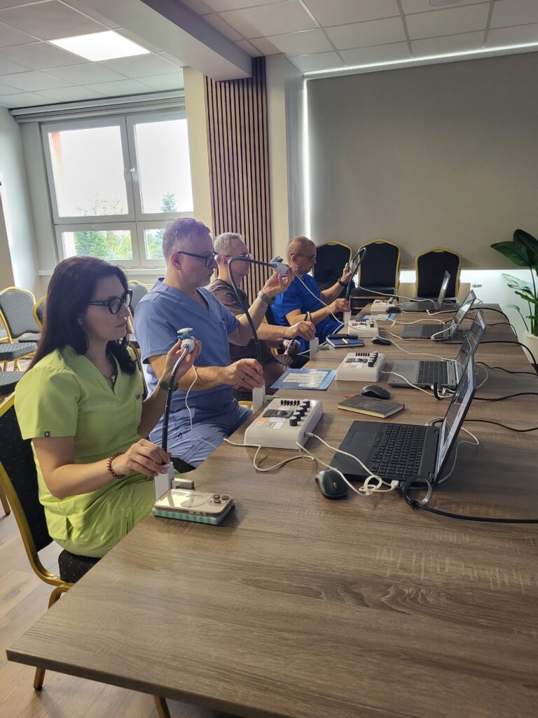 lekarze przy stolikach ćwiczą na symulatorach