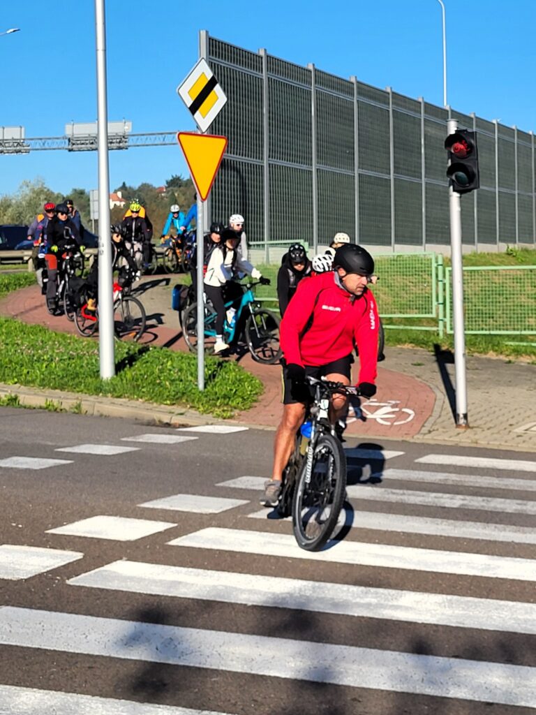 uczestnicy przejeżdżają drogą rowerową przez skrzyżowanie