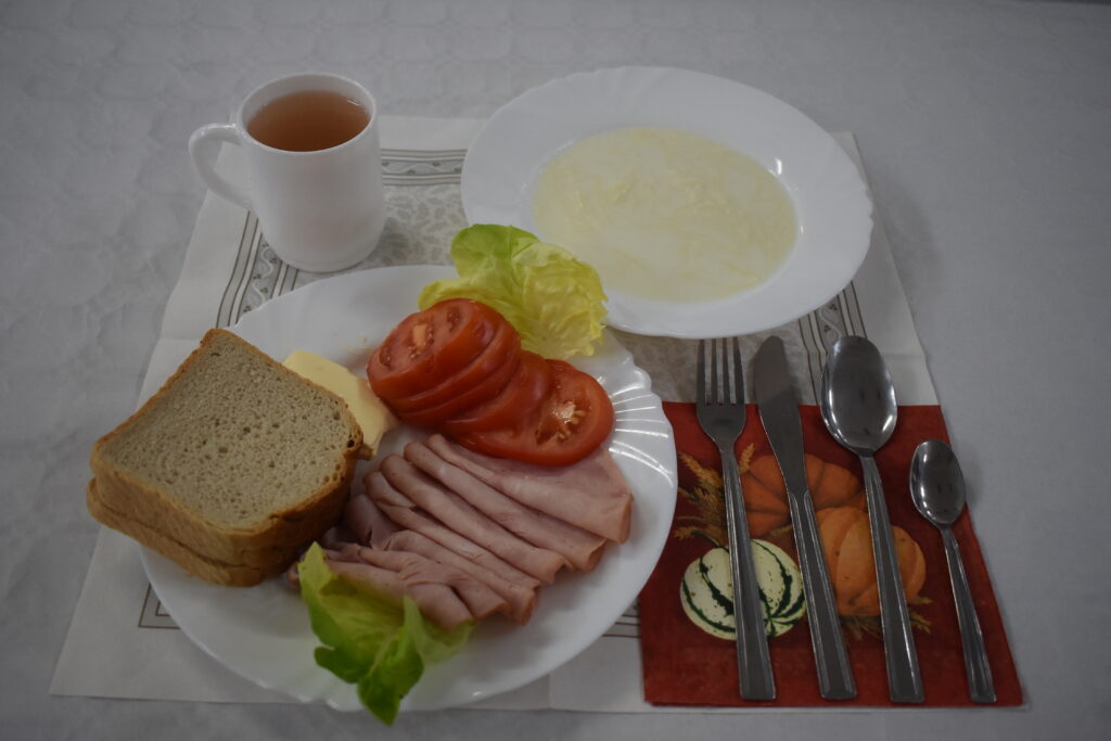 zupa mleczna, herbata, chleb w kromkach, masło, wędlina w plastrach, pomidor,