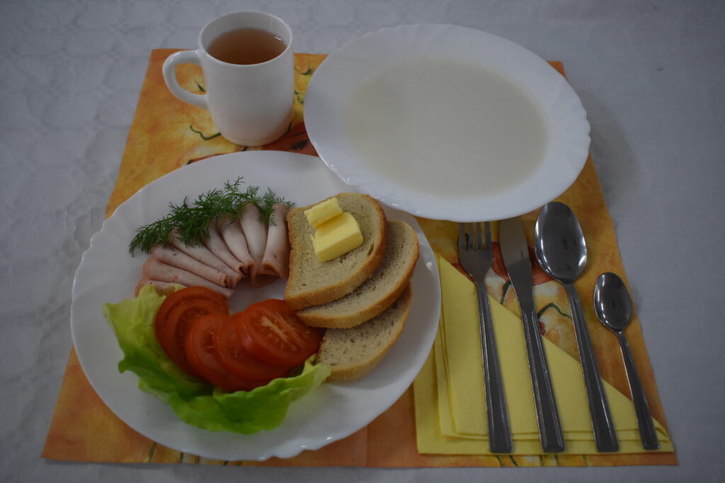 zupa mleczna, herbata, chleb w kromkach, masło, wędlina w plastrach, pomidor,