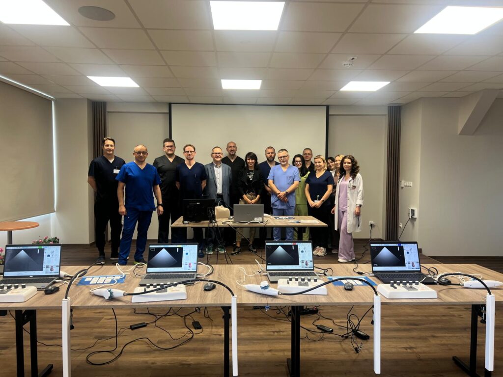 uczestnicy szkolenia na zdjęciu grupowym na sali szkoleniowej, przed nimi na stołach symulatory