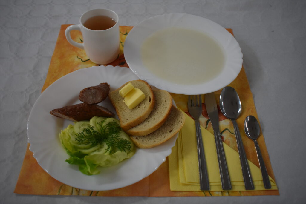 zupa mleczna, herbata, chleb w kromkach, masło, kiełbasa, ogórek