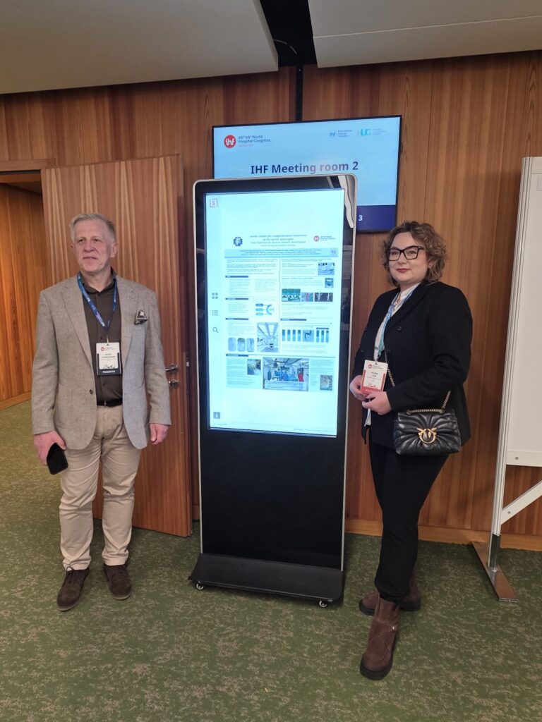 przy ekranie prezentującym plakat szpitala stoi Piotr Stabiszewski i Sylwia Zub