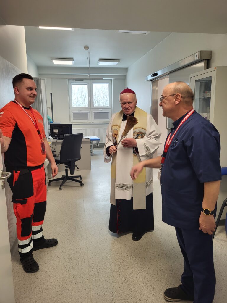 biskup święci pokój zabiegowy, obok ratownik i lekarz