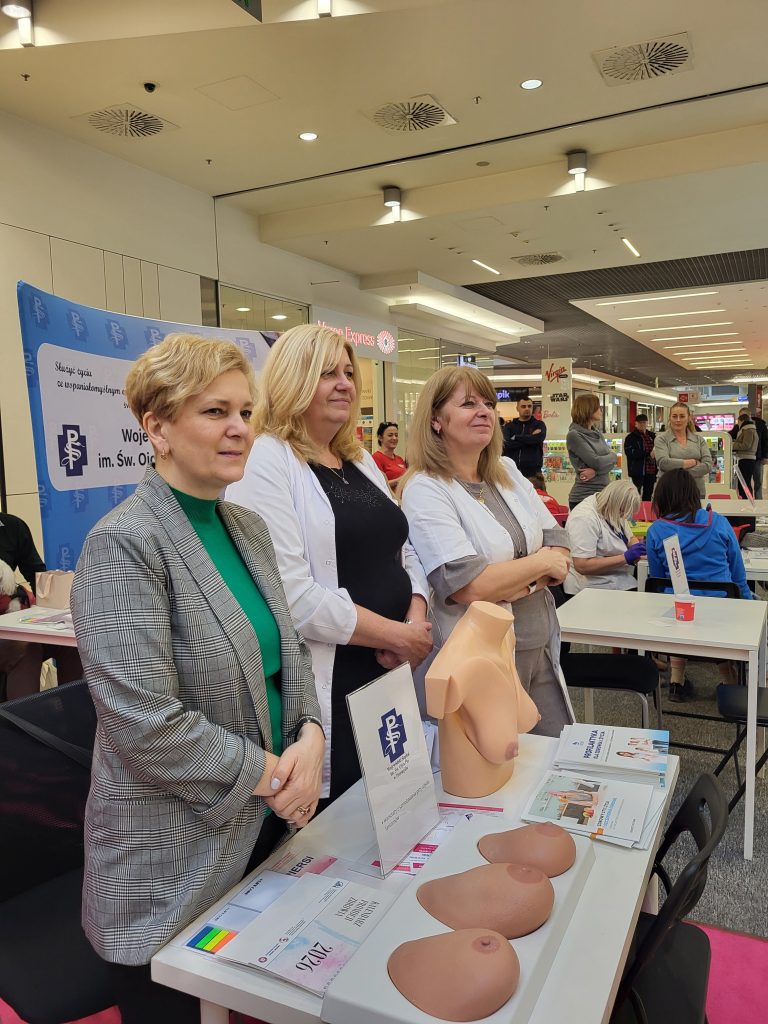 3 pielęgniarki stoją przy stoisku z fantomami do nauki samobadania piersi
