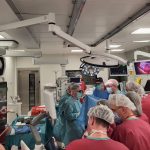 sala operacyjna, szeroki kadr, dużo osób personelu medycznego wokół stołu operacyjnego