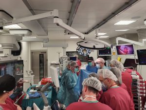 sala operacyjna, szeroki kadr, dużo osób personelu medycznego wokół stołu operacyjnego