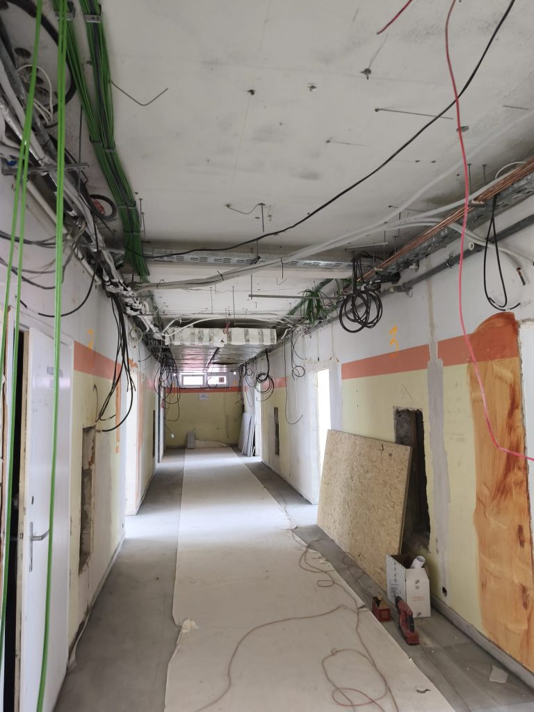 korytarz w remoncie, odsłonięte przewody i instalacje, zdarte farby