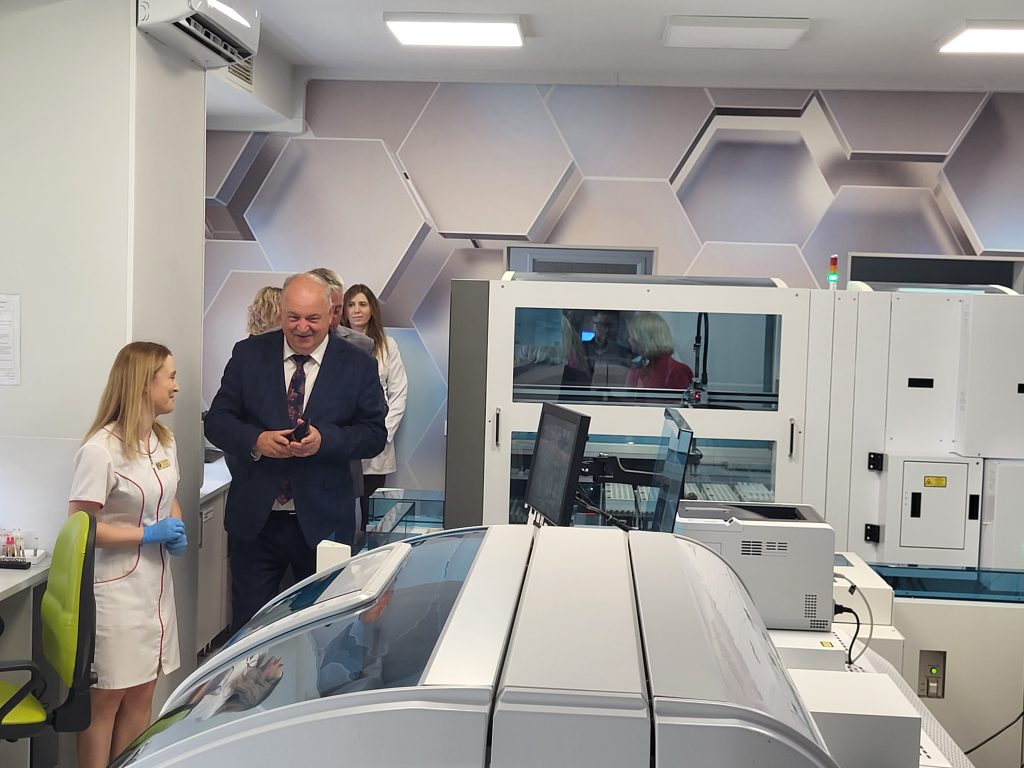w pracowni biochemii wśród urządzeń wicemarszałek Piotr Pilch, obok pracownica pracowni opowiada o nich, z tyłu inne osoby