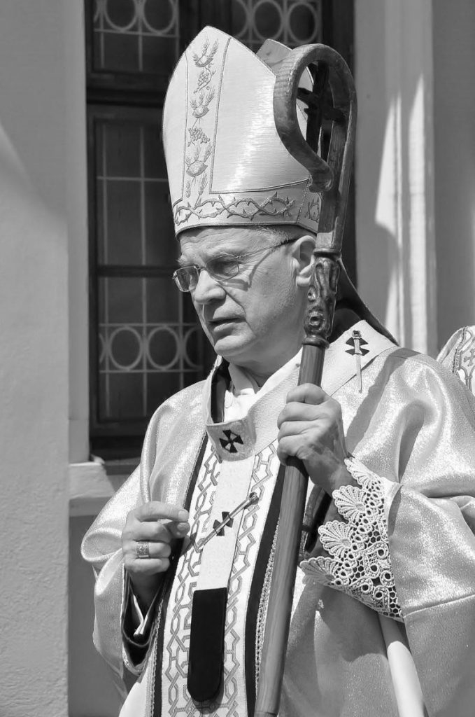 czarno-białe zdjęcie arcybiskupa Michalika idącego w procesji w sztach liturgicznych i pełnym stroju biskupim: z pastorałem i mitrą