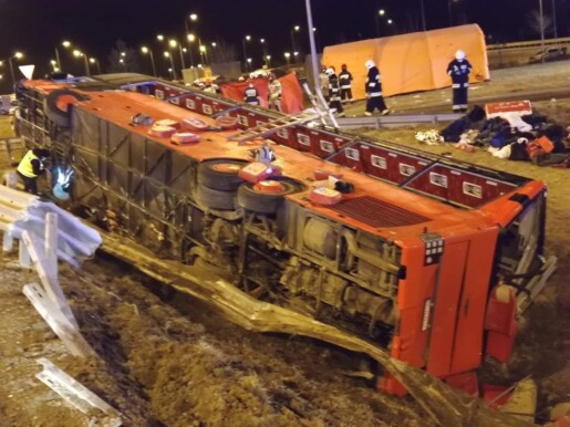 przewrócony czerwony autokar leży na boku w rowie, widać duże uszkodzenia