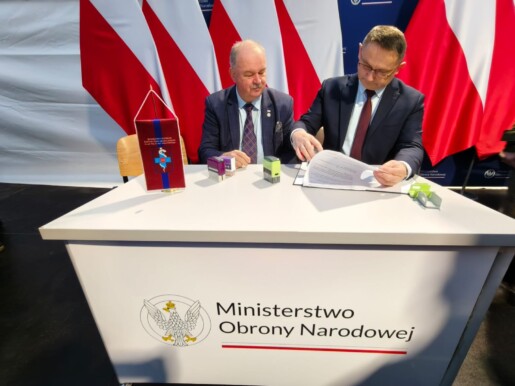 przy stoliku zastepca dyrektora i wicemarszałek województwa podpisują porozumienie, za nimi białoczerwone flagi