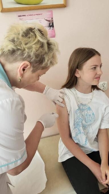 pielęgniarka szczepi dziewczynkę siedzącą na kozetce