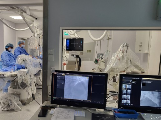 pracownia hemodynamiki, po lewej stronie lekarz wykonujący zabieg i pielęgniarka, po prawej monitory