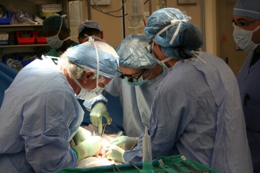 sala operacyjna, 3 osoby z personelu medycznego nad stołem operacyjnym